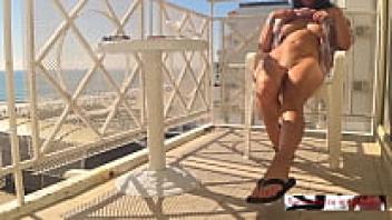 A lovely female was caught on camera masturbating on a hotel balcony close to a beach that was crowded with people.